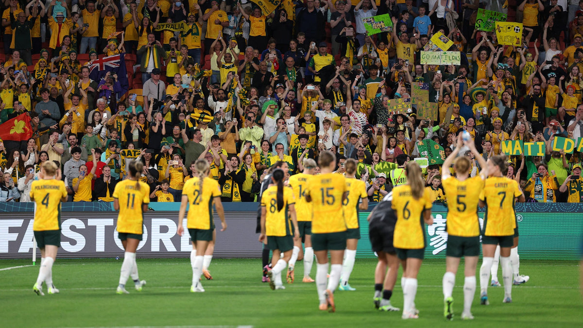 Womens football match with crowd cheering in the background
